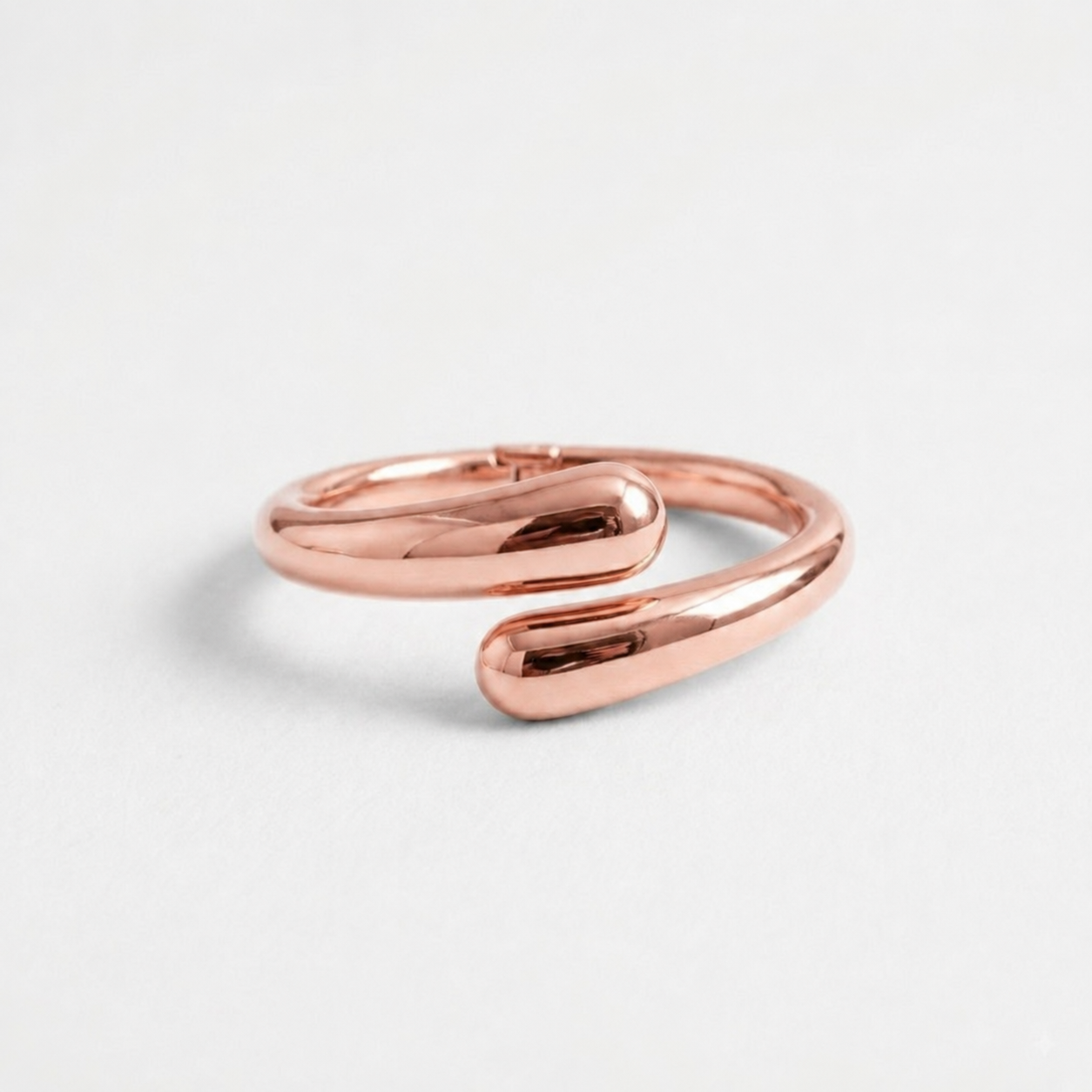 Rose gold open cuff bangle bracelet for women with a polished sculptural teardrop design, photographed on a clean white background.
