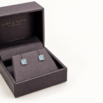 Sky blue topaz stud earrings in Aura and Faith presentation box, angled view