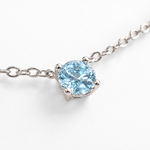 Close-up of round blue topaz white gold necklace setting and chain