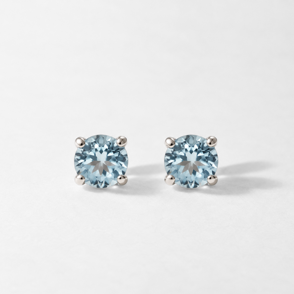 Pair of round sky blue topaz stud earrings in white gold, front view