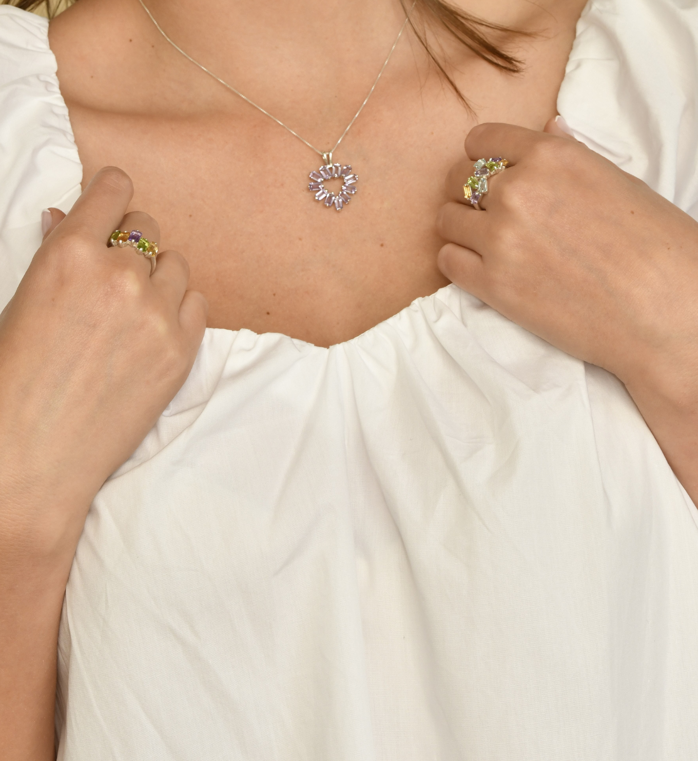 Woman with white top, wearing baguette gemstone jewelry set, with diamonds, peridot, and citrine. Perfect for a sweetheart neckline.
