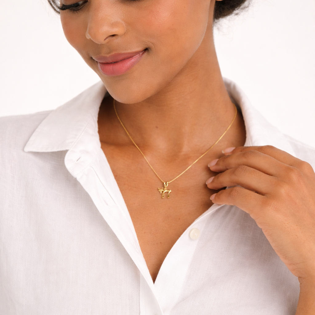 Woman wearing a gold necklace with a small pendant against a white background