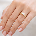 Gold ring with a diamond on a hand against a neutral background